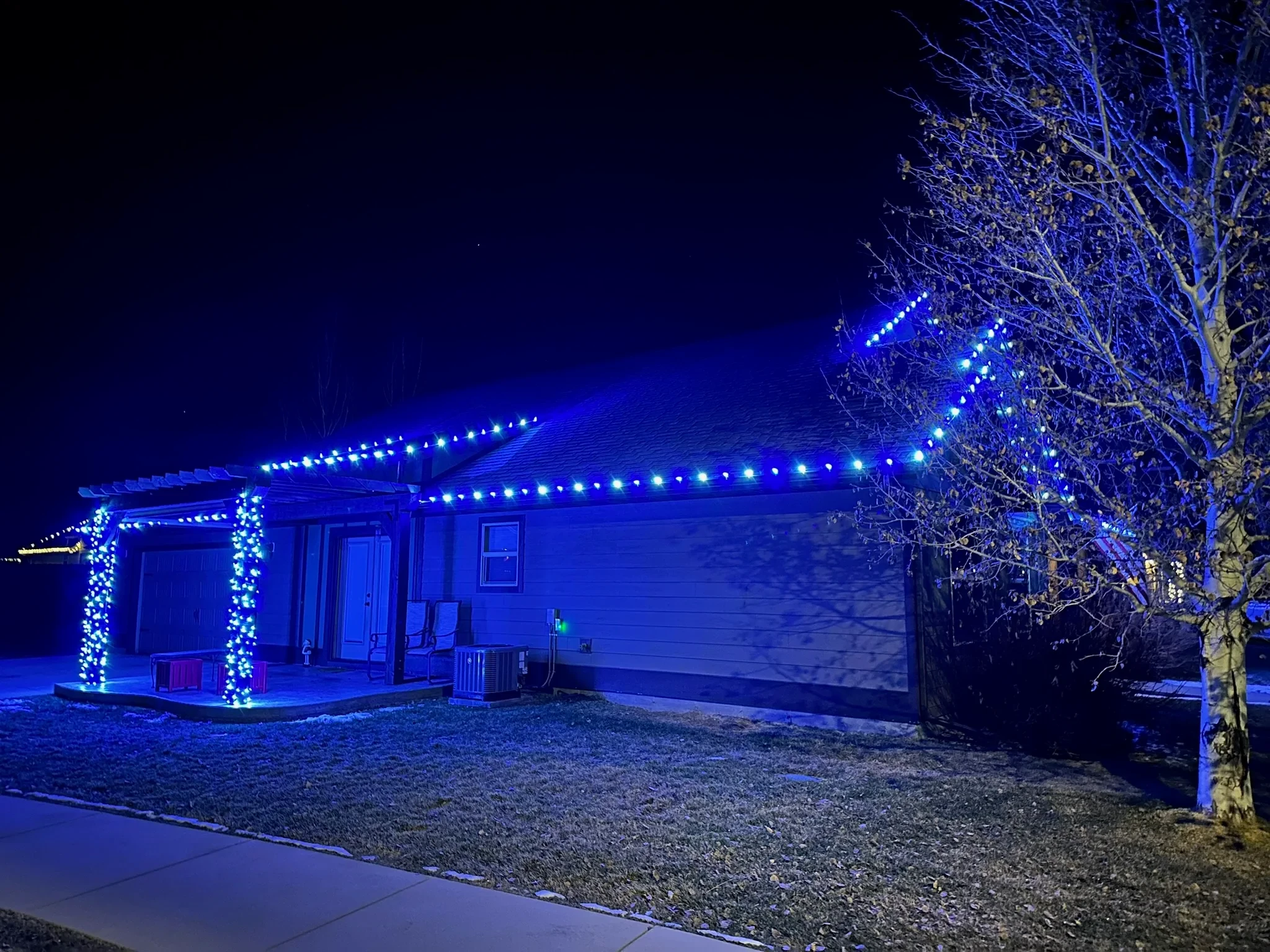 Home with blue lights along the roofline and wrapped around the porch pillars.