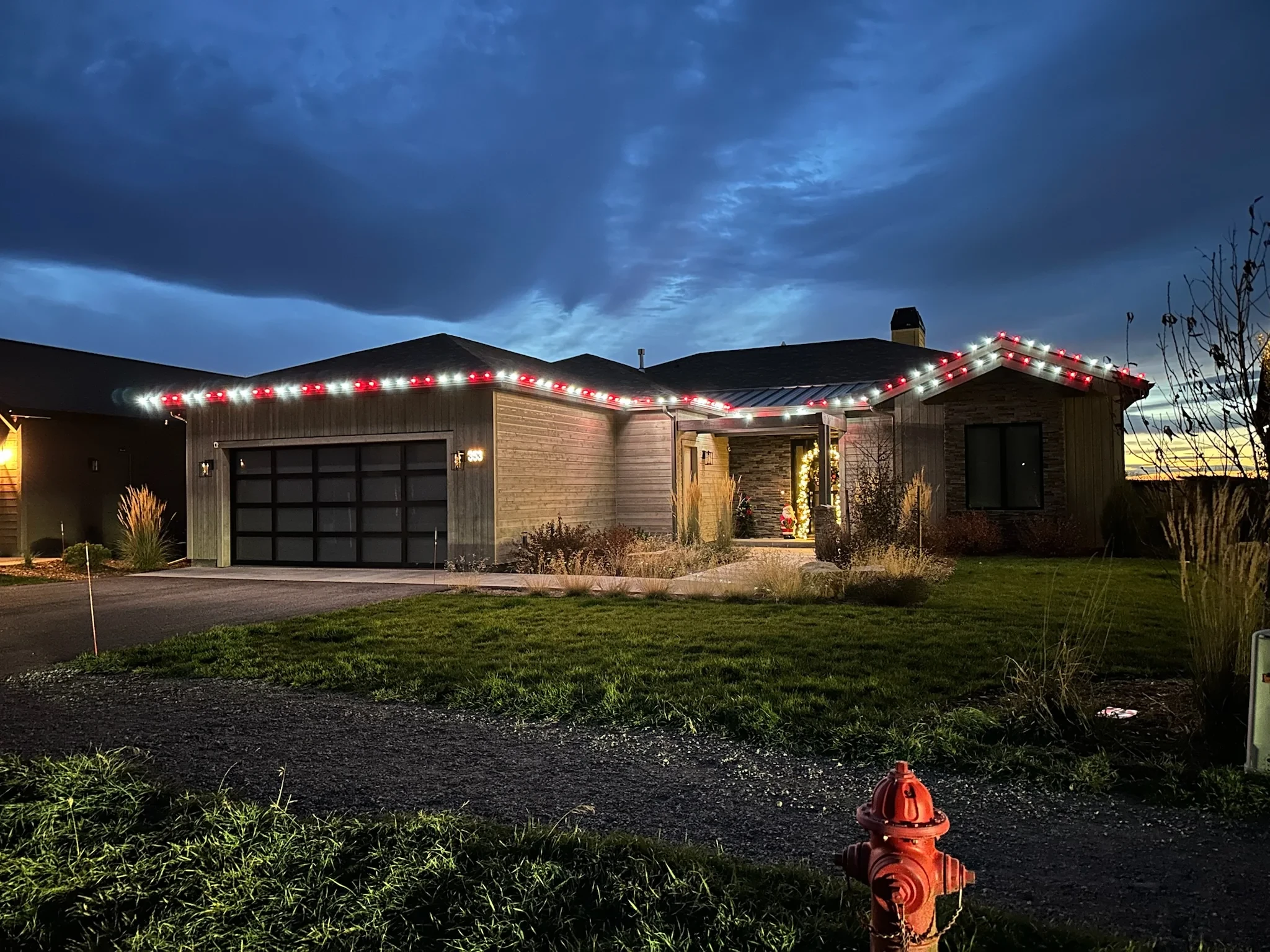 Single-story home with red and white Christmas lights along the roofline.