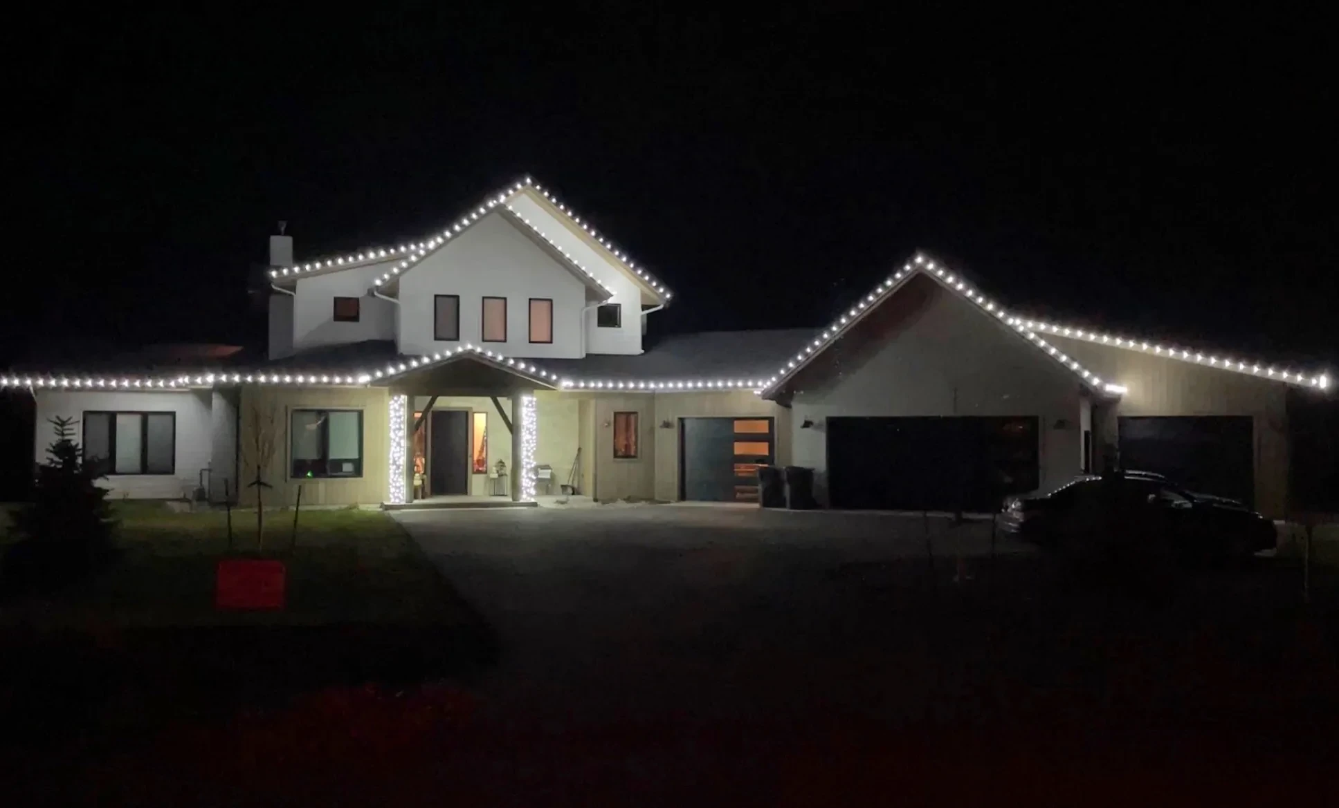 Two-story home with white lights tracing every roof edge and gable.